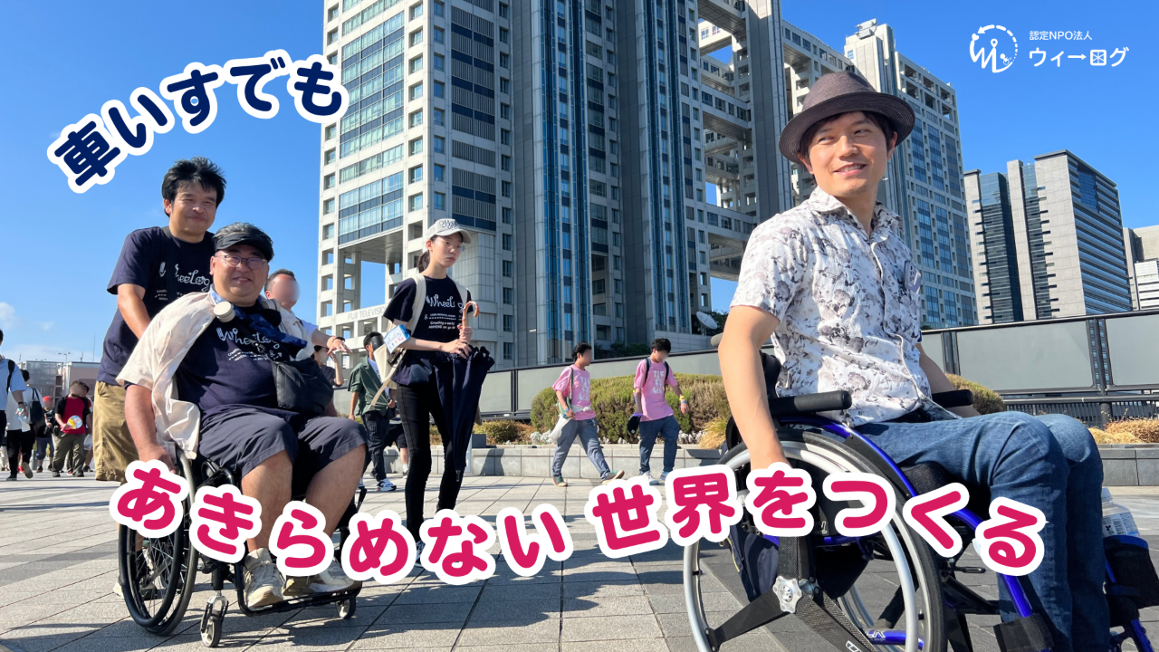 車いすユーザーと仲間たちが高層ビルの前を笑顔で進む写真に「車いすでも あきらめない世界をつくる」の文字