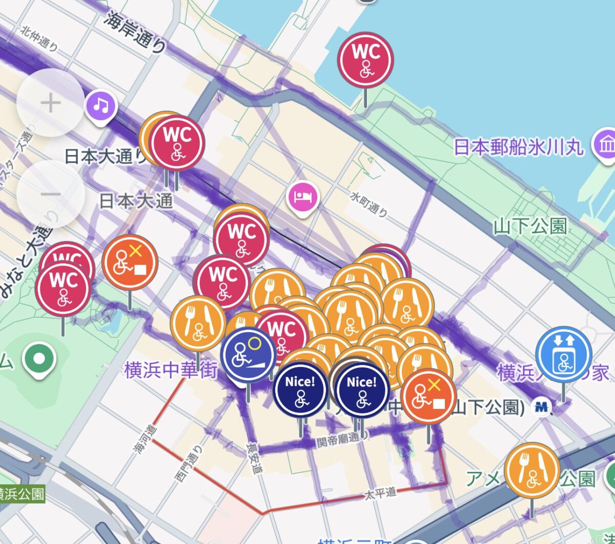 WheeLog!アプリのマップ画面のスクリーンショット。横浜中華街の地図上に、飲食店（オレンジ）、トイレ（ピンク）、おすすめスポット（青）など、非常に多くのバリアフリー情報のアイコンが密集してプロットされている様子。